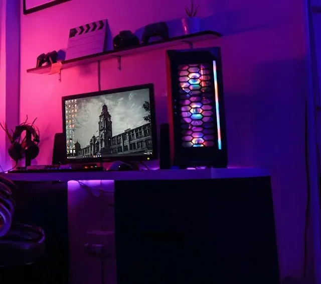 Rincón de streaming con luces violeta y rosa, monitor y PC con luces RGB